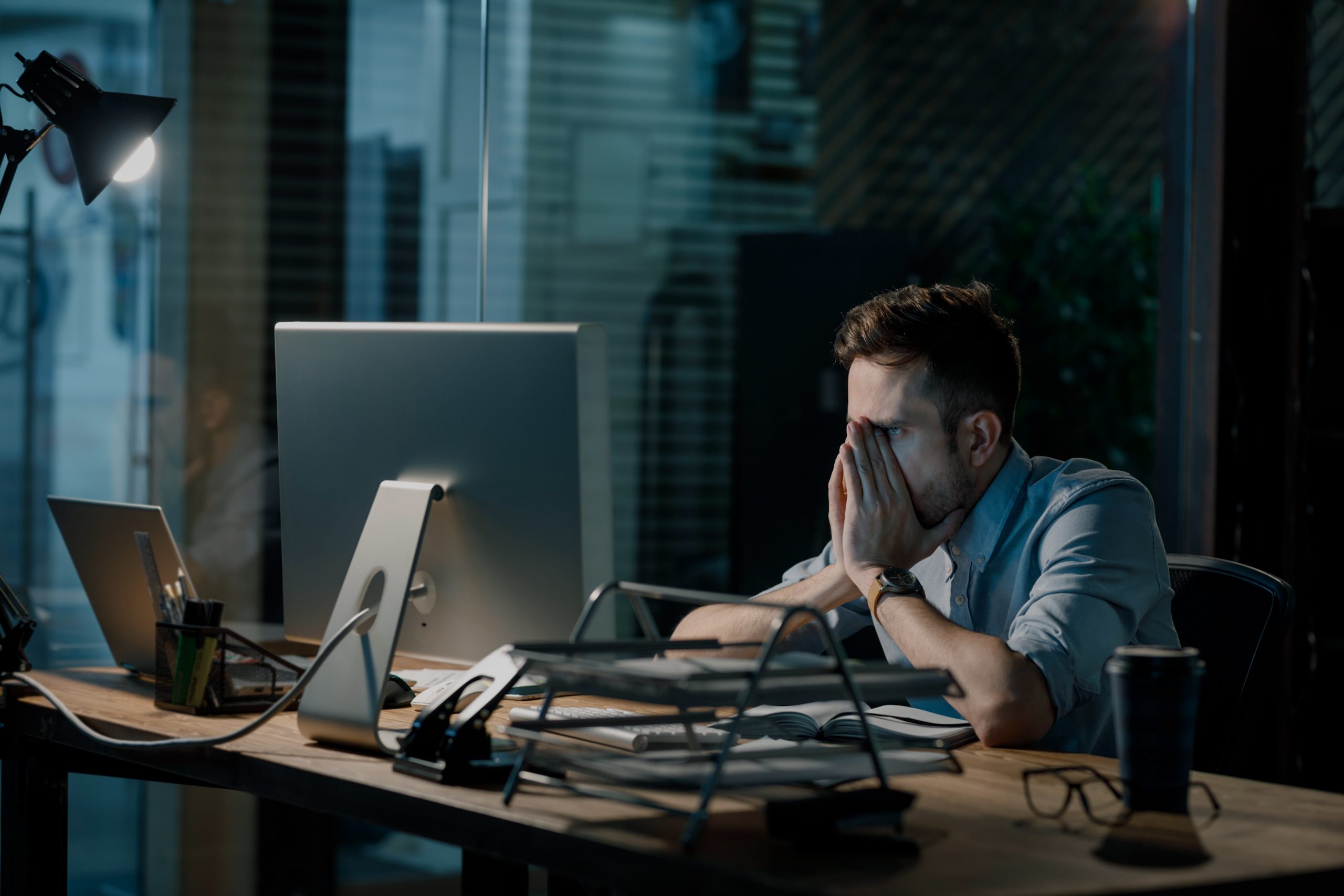 overwhelmed-man-sitting-at-desk-looking-at-computer-at-night